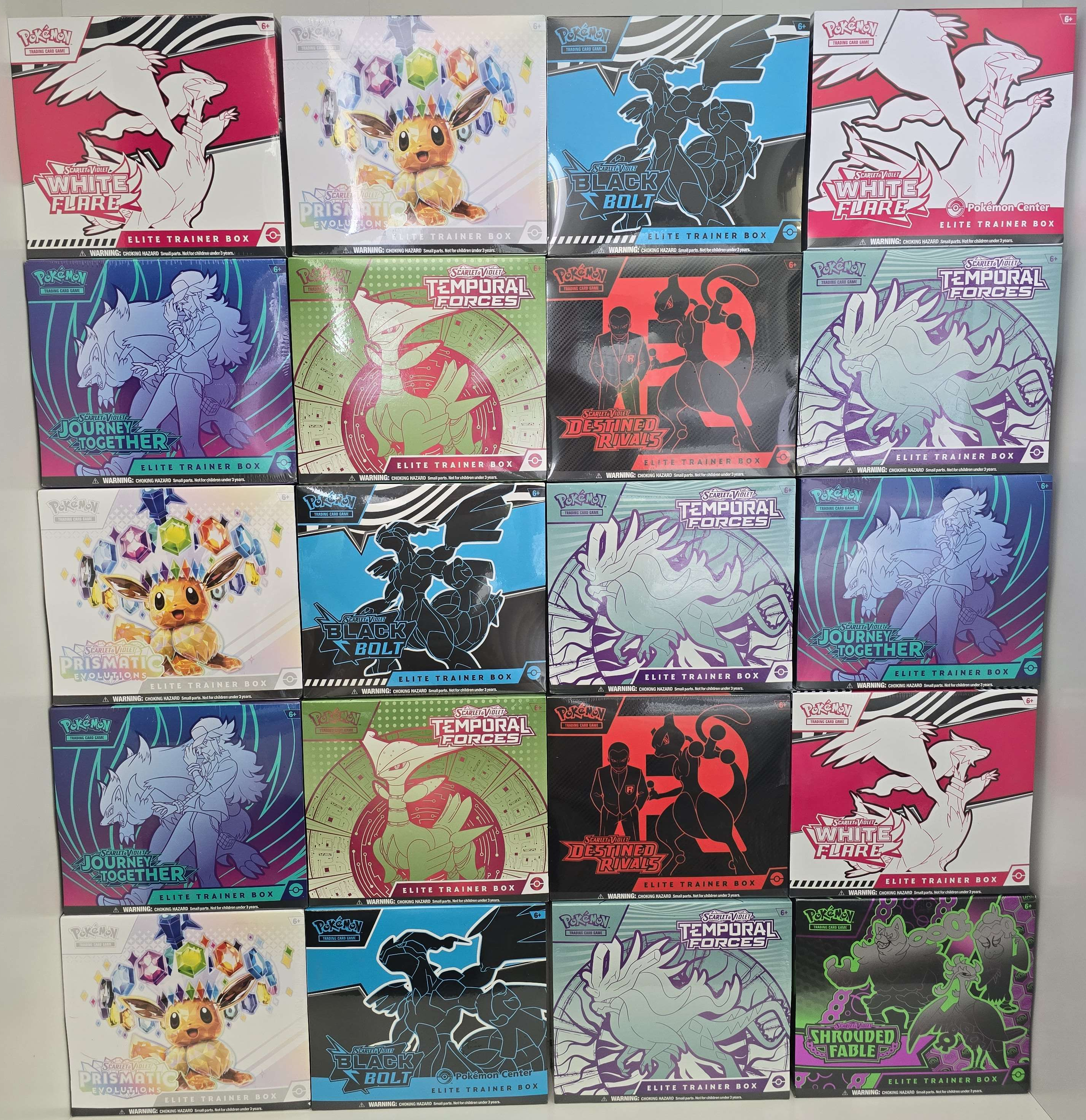A wall display of Pokemon Elite Trainer Boxes including White Flare, Black Bolt, Prismatic Evolutions, Journey Together, Temporal Forces, Destined Rivals, and Shrouded Fable